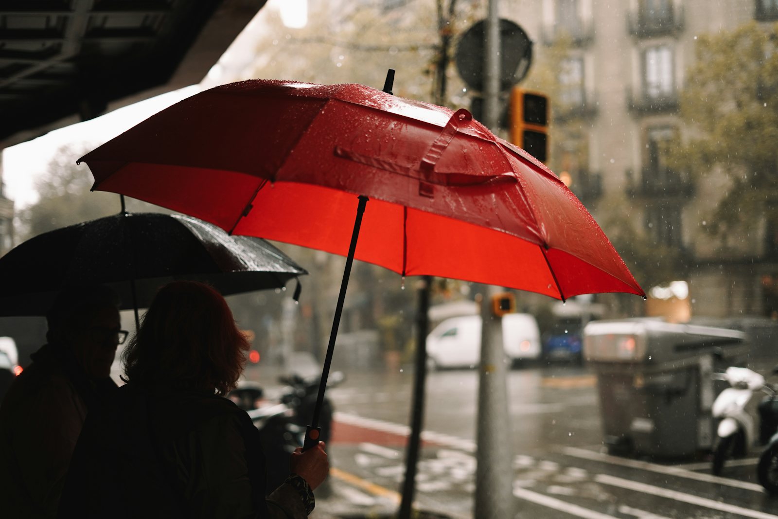 Person holding a red umbrella in the rain