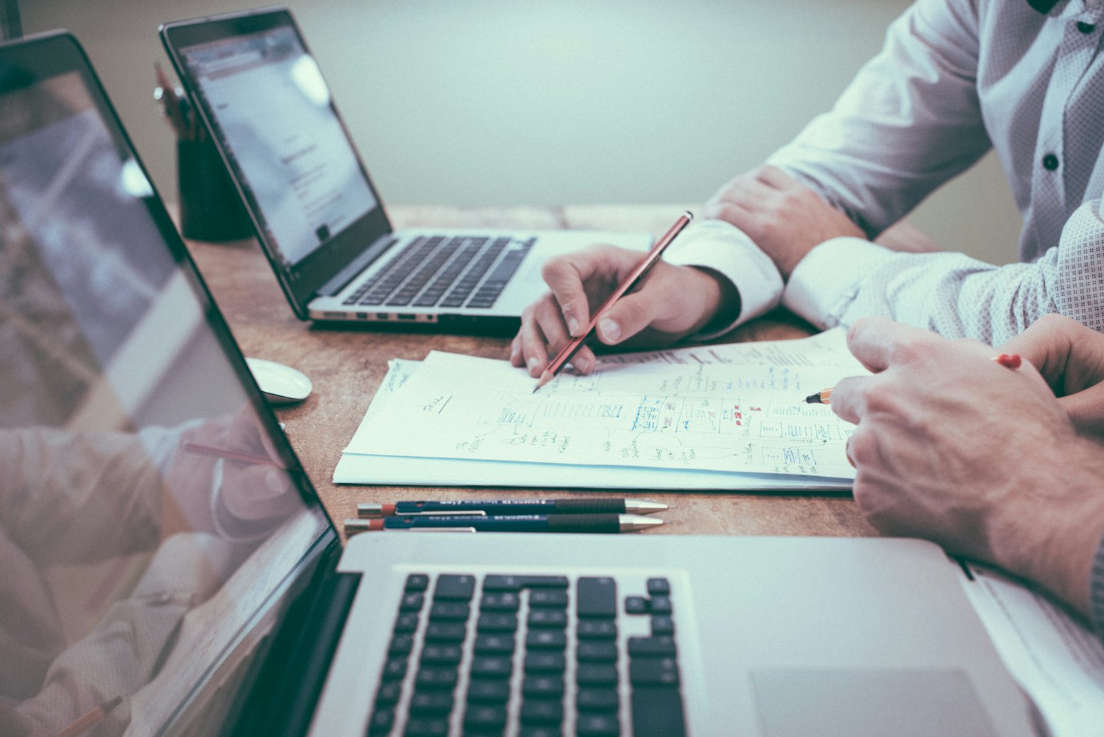 Person planning finances with pencil beside laptop