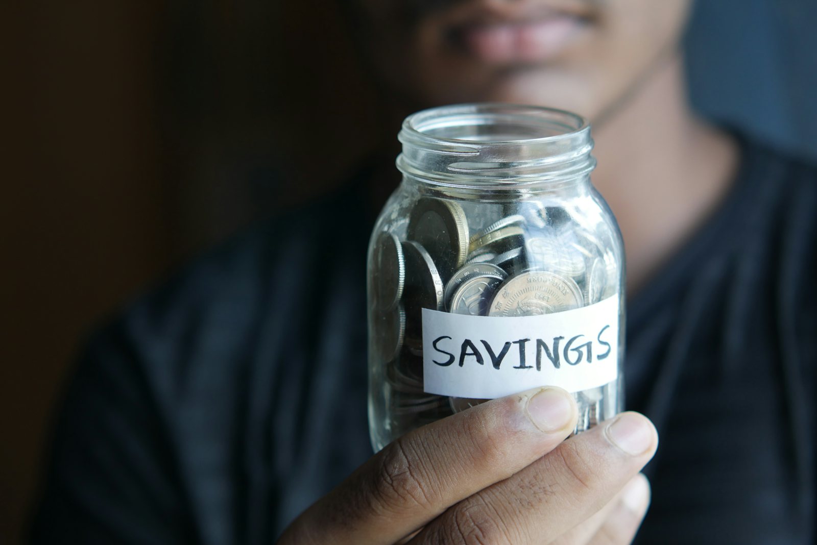 Hand holding a jar labelled savings