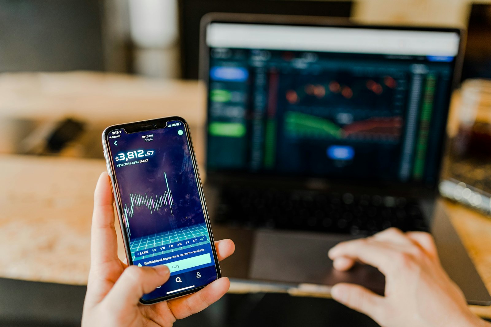 Person checking an investment portfolio on phone and laptop